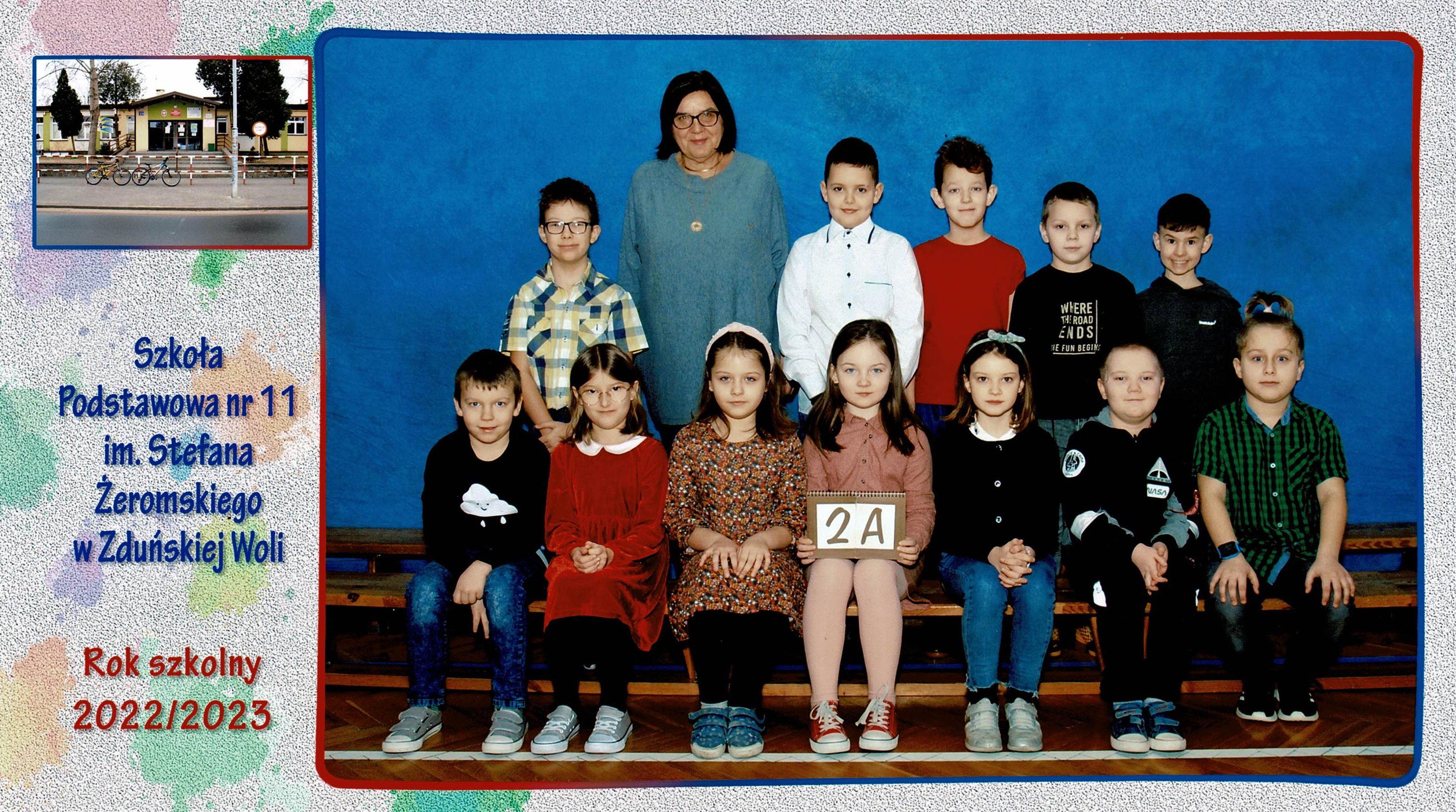 Uczniowie klasy 2A, dziewczynki i chłopcy siedzący na ławce z tabliczką "klasa 2a"