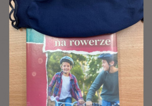 na okładce książki dwaj chłopcy na rowerach, tytuł zakryty maseczką