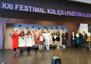 dzieci na tle napisu XXI Festiwal Kolęd i Pastorałek